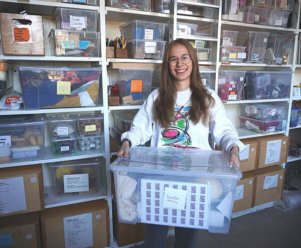 FSJ-lerin Maren Daub hält eine Kiste mit Materialien für die Museumspädagogik.