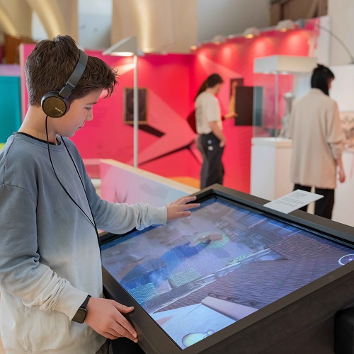 Jugendlicher in der bunten Ausstellung spielt Computerspiel